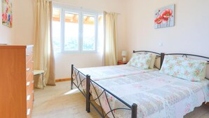 Une chambre à coucher avec un lit, des rideaux, une fenêtre, un tableau et une commode.