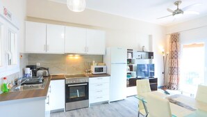 Une cuisine moderne avec des meubles blancs, un four à micro-ondes, une cuisinière et un coin repas comprenant une table et des chaises en verre.