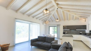 A spacious living area with a high ceiling, a sofa, a dining table, and a kitchen area. - Villa Loki in Kremithas (Kremithas)