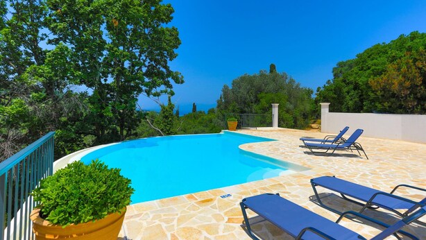 A swimming pool with lounge chairs, surrounded by stone tiles and greenery. - Villa Loki in Kremithas (Kremithas)