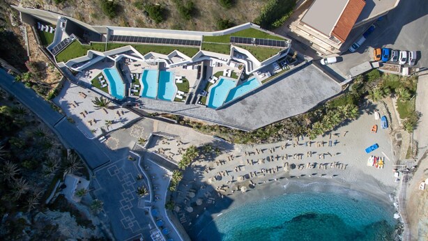 An aerial view of a coastal resort with multiple swimming pools, a beach area, and a parking lot. - Made By The Sea Villa 5 (Mades)