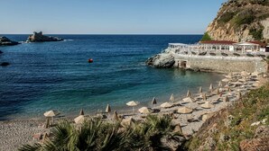 Ein Strand mit Sonnenschirmen und ein Gebäude mit rotem Dach mit Blick auf das Meer.