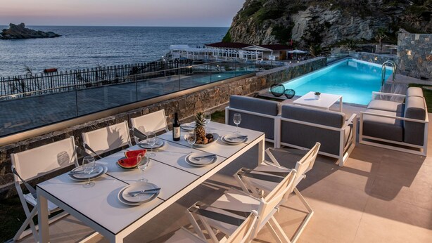 Ein Essbereich am Pool mit Blick auf das Meer, einen Pool und eine felsige Klippe.