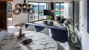 Ein moderner Essbereich mit einem Marmortisch, weißen Stühlen und Blick aufs Meer.