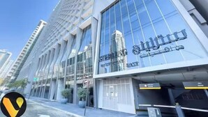 A modern building with large glass windows and a sign in Arabic. - Vogue | Sterling near Dubai Mall | Burj Khalifa (Dubai)