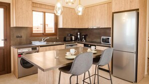 A modern kitchen with wooden cabinets, stainless steel appliances, a central island with chairs, and pendant lighting. - Villa Kerastis in Malatya (Malatya)