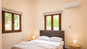 Une chambre à coucher comprenant un lit, deux tables de chevet, une fenêtre et un appareil de climatisation.