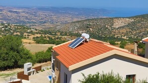Un bâtiment moderne avec un toit rouge, des panneaux solaires et une vue sur un paysage vallonné.