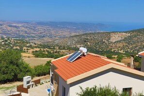A modern building with a red roof, solar panels, and a view of a hilly landscape. - Villa Kition in Malatya (Malatya)