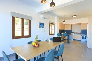 Una cocina moderna con lavadora, un comedor con mesa y sillas, y una computadora portátil sobre la mesa.
