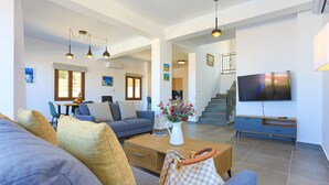 A spacious living room with a sofa, coffee table, and a TV. There is a staircase leading to another level. - Villa Salina in Malatya (Malatya)