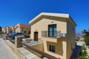 Un edificio residencial moderno con balcón, pared de piedra y vistas despejadas del paisaje circundante.