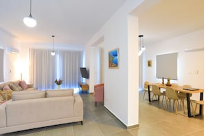 A modern living room with a sofa, a dining table with chairs, a flat-screen TV, and a painting on the wall. - Villa Aeria in Malatya (Malatya)