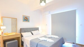 Une chambre à coucher avec un lit, une table de chevet et un petit tabouret.