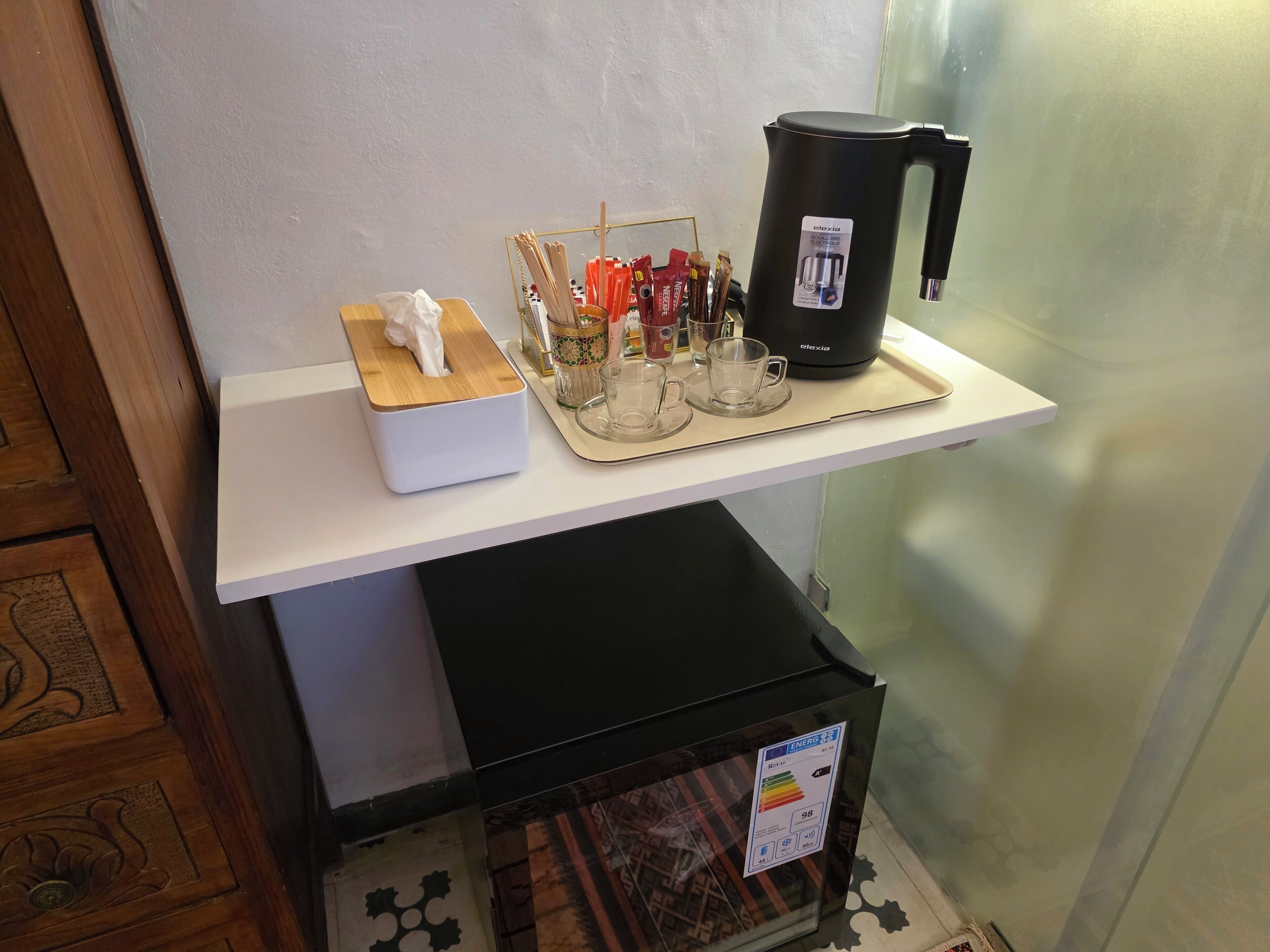 Un coin cuisine équipé d’une machine à café, d’une boîte de mouchoirs et d’un plateau avec des tasses et des couverts.