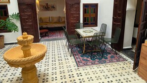 A traditional Moroccan interior with a stone fountain, a patterned rug, and a seating area with cushions. - Riad Boutique Baba (Rabat)