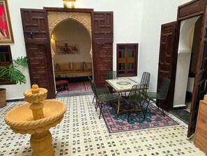 A traditional Moroccan interior with a stone fountain, a patterned rug, and a seating area with cushions. - Riad Boutique Baba (Rabat)