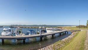 A marina with several boats docked, a wooden pier, and a grassy area beside the water. - "Rotmilan," a thatched-roof vacation home with a sauna and fireplace in a quiet location on Rügen (Neuenkirchen)