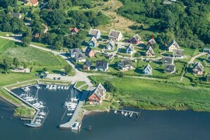 An aerial view of a lakeside village with houses, a marina, and boats. - "Rotmilan," a thatched-roof vacation home with a sauna and fireplace in a quiet location on Rügen (Neuenkirchen)