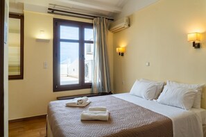 Une chambre d’hôtel avec un lit, une fenêtre avec des rideaux, des lampes fixées au mur et une vue sur l’extérieur.