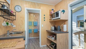 Ett litet, praktiskt kök med träpanel på väggarna, en diskho, en mikrovågsugn och en brödrost.