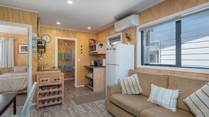 Ett kompakt bostadsutrymme med ett litet kök, en matplats och en soffa med kuddar.