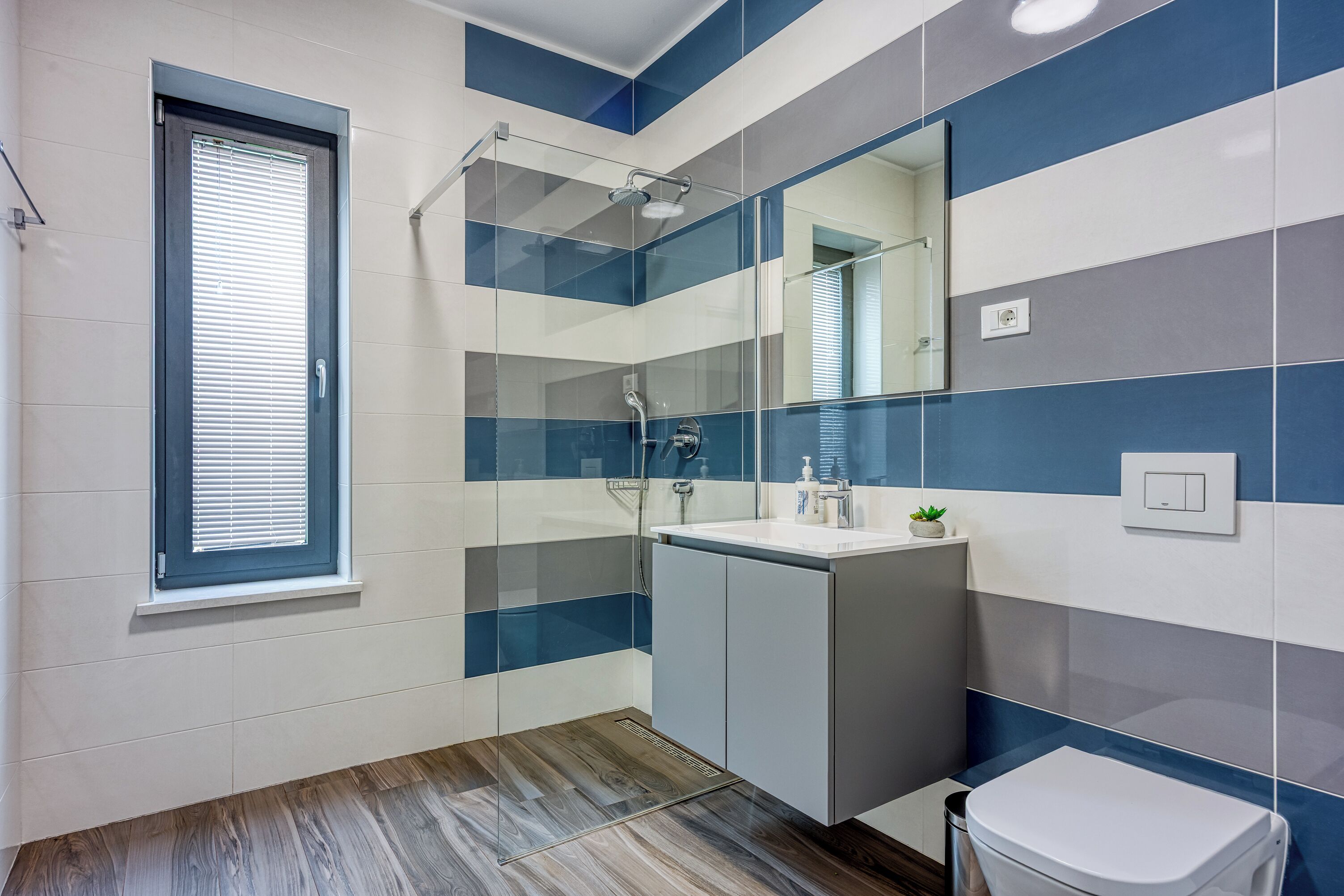 A modern bathroom with a shower, toilet, and sink.