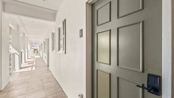 A hallway with a door, a light switch, and a security camera.