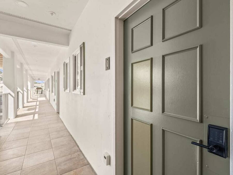 A hallway with a door, a light switch, and a security camera.