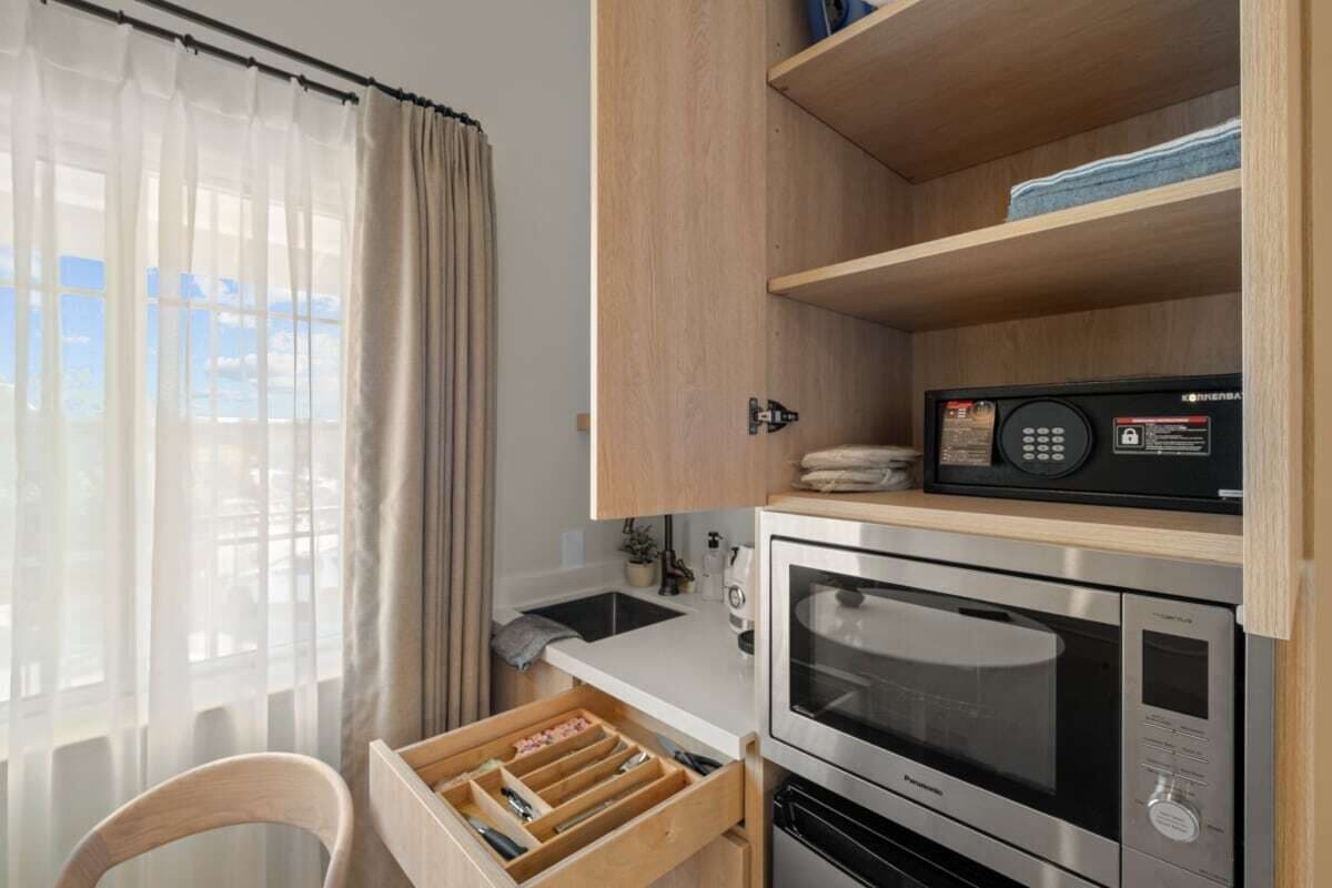 A compact kitchen with a microwave, oven, and wooden cabinets.