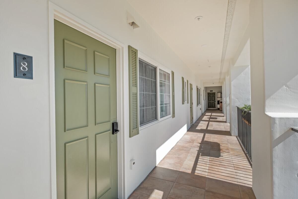 A corridor with green doors, a tiled floor, and a number '8' sign.