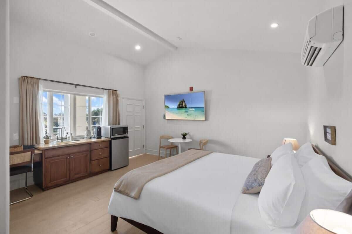 A bedroom with a bed, bedside table, and a window with curtains.