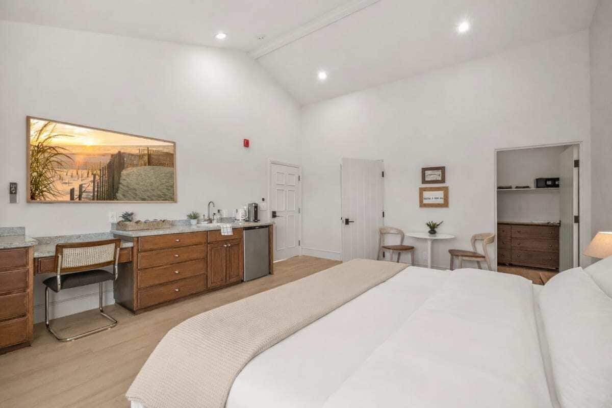 A bedroom with a bed, a desk, a chair, a small table, and a wardrobe.