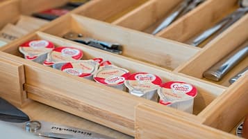 A wooden drawer containing coffee creamer tubes and a pair of scissors.