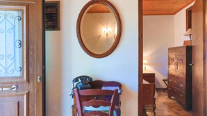 A room with a wooden door, a mirror on the wall, a wooden dresser, and a chair with a telephone. - Old Stone House in Nisaki (Nisaki)
