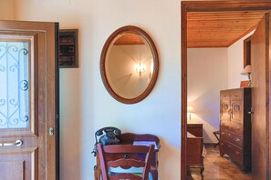 A room with a wooden door, a mirror on the wall, a wooden dresser, and a chair with a telephone. - Old Stone House in Nisaki (Nisaki)