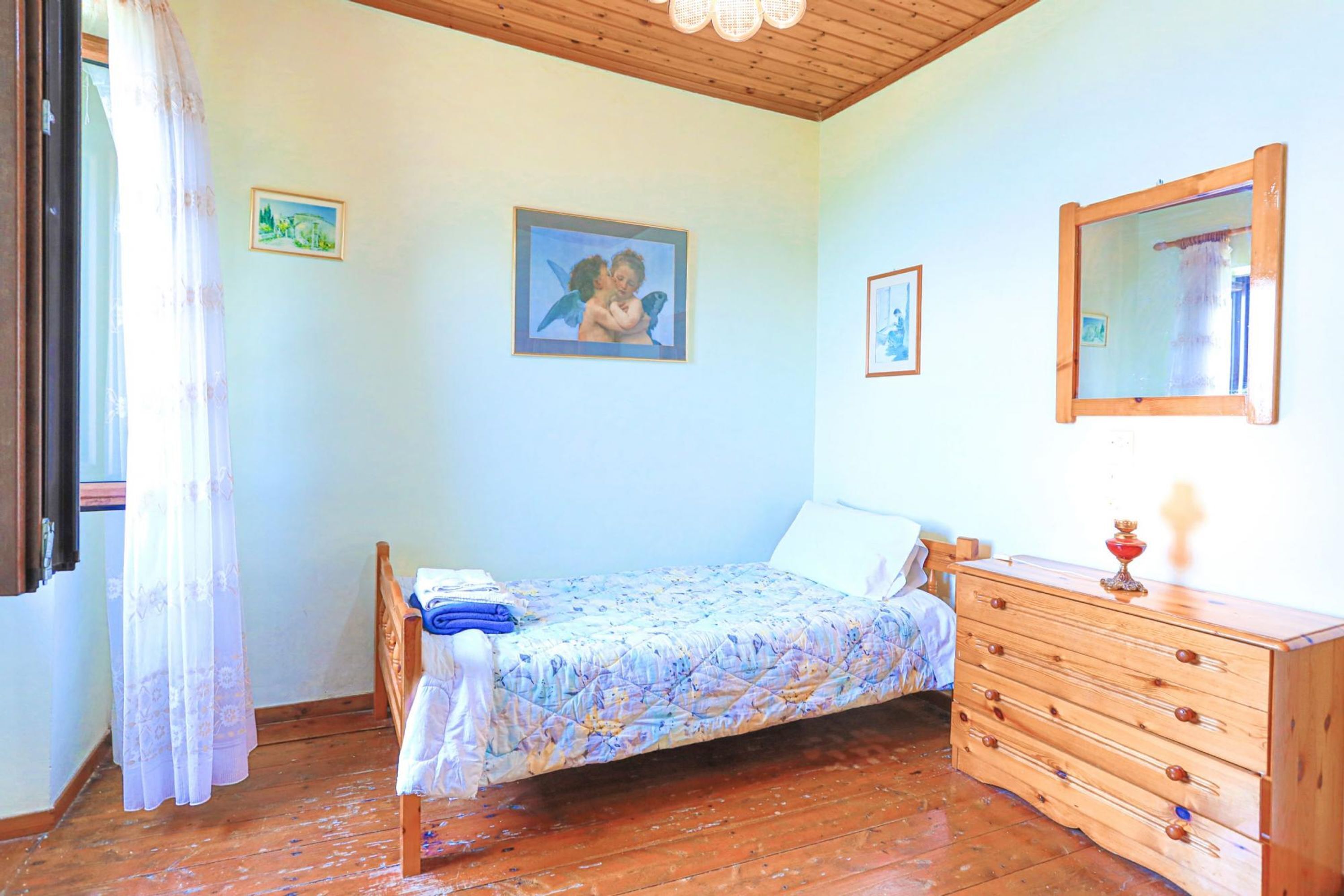 Un dormitorio con una cama, cómoda de madera y un espejo.
