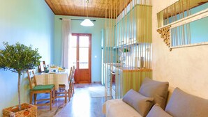 Une pièce avec un plafond en bois, un canapé, une table à manger avec des chaises et une plante suspendue.