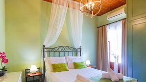Un lit bien fait, avec des oreillers verts, une lampe de chevet et une serviette enroulée posée sur le lit.