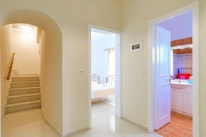 A hallway leading to a bedroom with a bed and a bathroom with a sink and mirror. - Vista Mare Ilios in Nisaki (Nisaki)