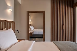 A hotel room with a bed, bedside lamp, wooden headboard, and a mirror. - Beachfront Alassa Villas w/ Private Pools Complex (Agios Dimitrios)