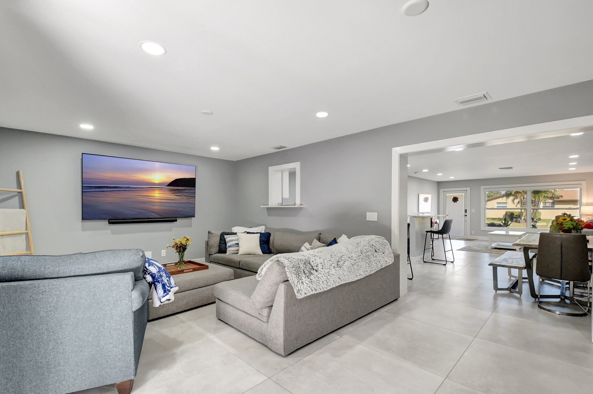 A modern living room with a grey sofa, a coffee table, and a flat-screen TV mounted on the wall.
