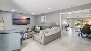 Un salon moderne avec un canapé gris, une table basse et un téléviseur à écran plat fixé au mur.