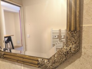 A mirror with ornate gold detailing and a reflection of a room with a white wall and a door. - TULLINS • Equipped T2 between Grenoble and Valence - For professionals, tourism and weddings (Tullins)