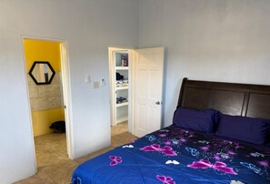 Ein Schlafzimmer mit Bett, Kleiderschrank und einer Tür zu einem Badezimmer.