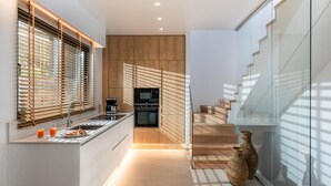 Eine moderne Küche mit Einbauofen, Kaffeemaschine und einer Frühstückstheke. Eine Treppe führt zu einer oberen Ebene.