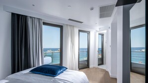 A modern hotel room with a large bed, a view of the sea, and a balcony. - Made By The Sea Villas 8 BDRM (Mades)