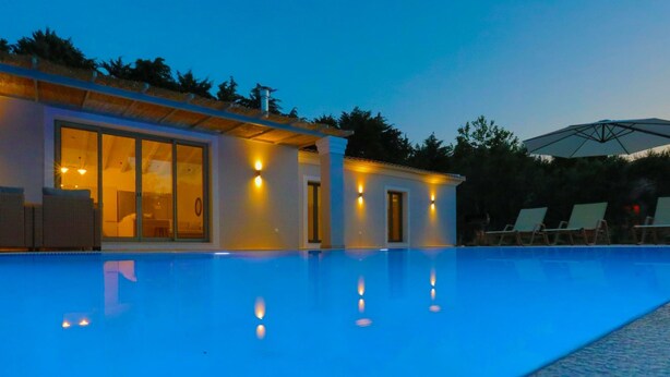 A modern building with a swimming pool, large windows, and outdoor seating. - Villa Jupeter in Corfu (Corfu)