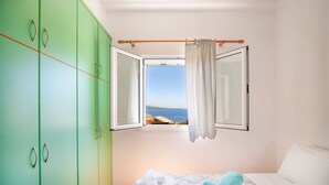 A bedroom with a bed, green wardrobe, and a window with a view of the sea. - Takis House in Katavolos (Katavolos)