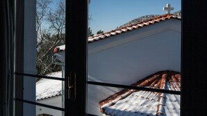 Une fenêtre donnant sur un bâtiment avec un toit recouvert de tuiles et surmonté d’une croix.